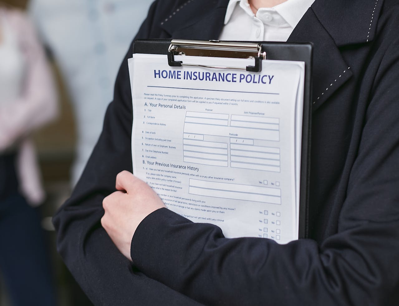 Close-up of a person holding a home insurance policy on a clipboard, captured indoors.